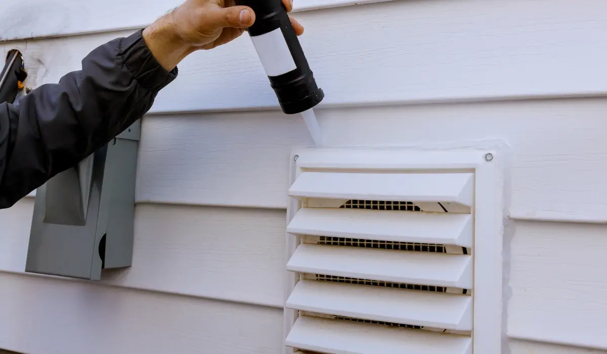 Technician sealing a dryer vent, a common entry point behind winter wildlife dangers in homes